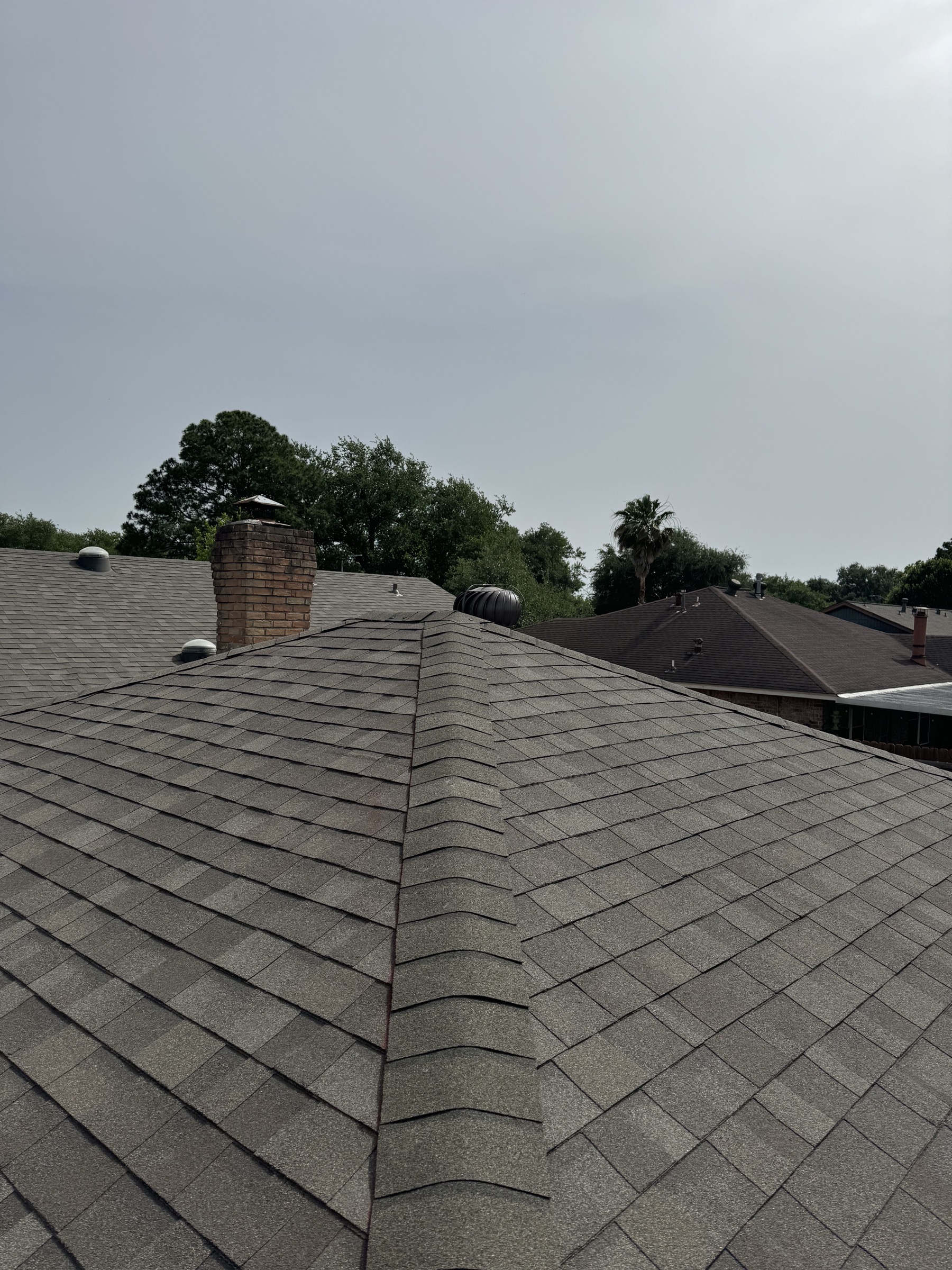 Deer Park home roof ridge with gray shingles and chimney