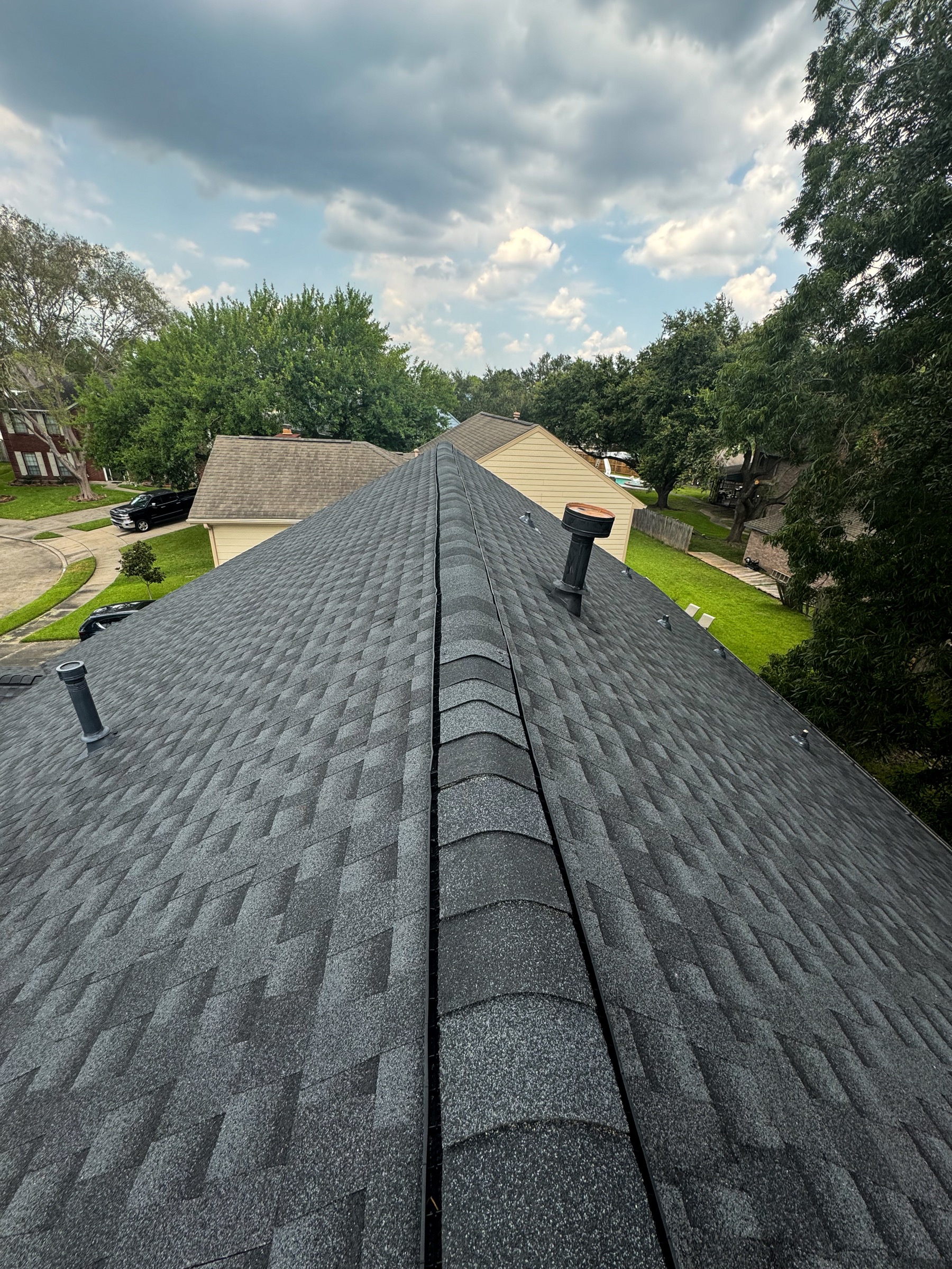 Friendswood home roof ridge with gray shingles under cloudy sky