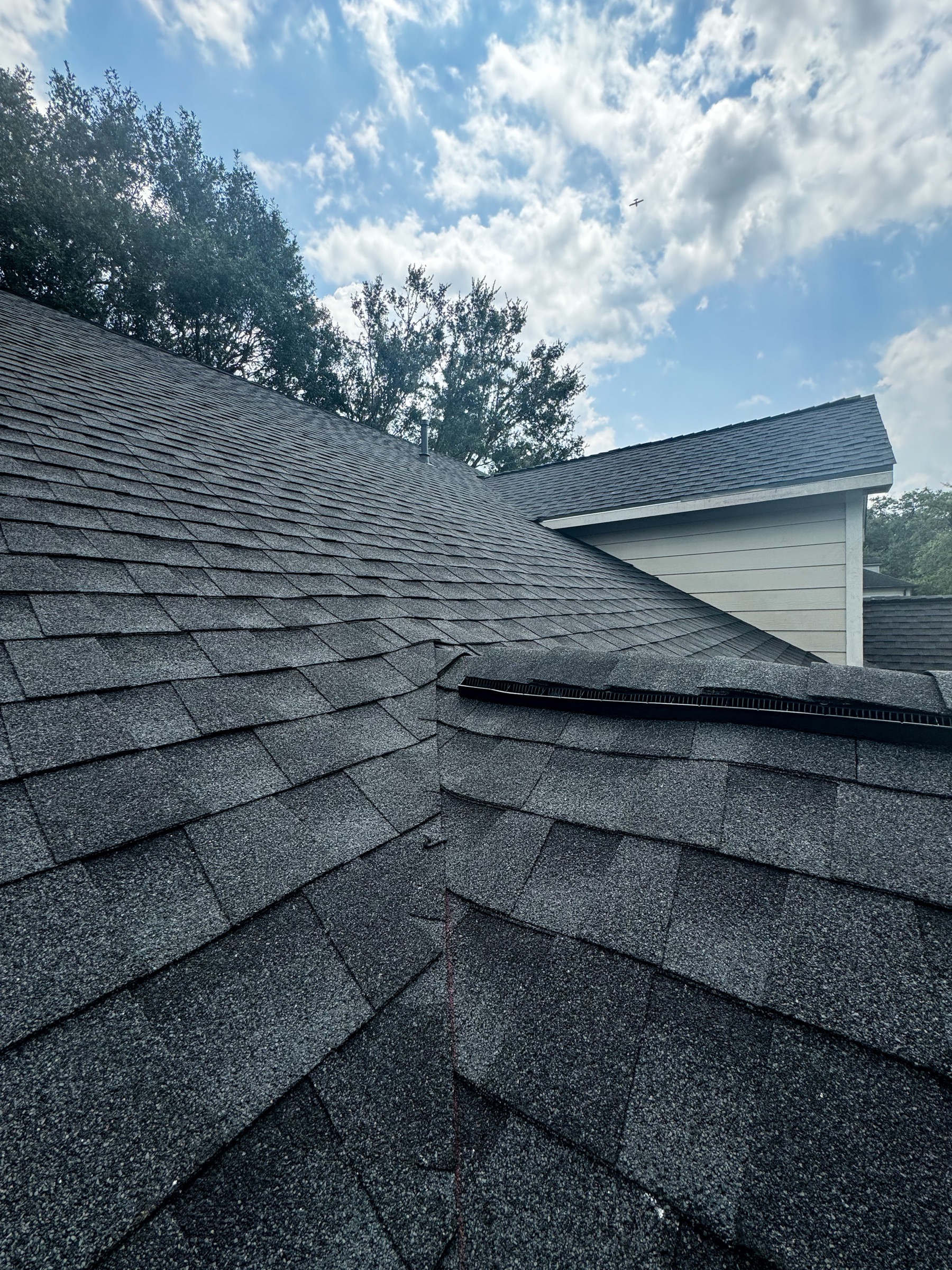 Close roof detail on Friendswood home showing shingle pattern and ridge ventilation